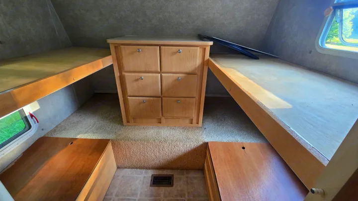 RV rental interior featuring bunk beds, a central dresser with six drawers, and two floor storage compartments.. Starcraft Homestead Settler 2004