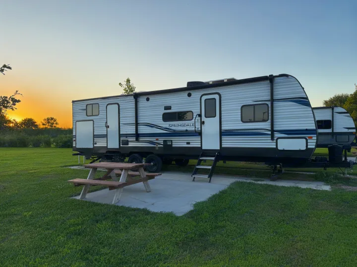 Scenic RV rental campsite at sunset: a Springdale travel trailer parked with a picnic table on a concrete pad.. Keystone RV Springdale 2022