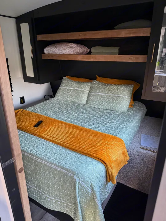 Cozy RV rental bedroom with a modern design, queen bed, smart storage, and earthy decor for a comfortable stay.. Keystone RV Springdale 2022