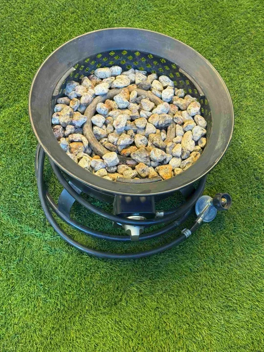 Portable gas fire pit with lava rocks on green artificial turf, ideal for RV rental and outdoor camping.. Propane 2021