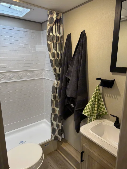 Explore this clean, well-equipped RV rental bathroom featuring a shower with curtain, toilet, and modern vanity with sink.. Coachmen Catalina Summit Series 8 2026