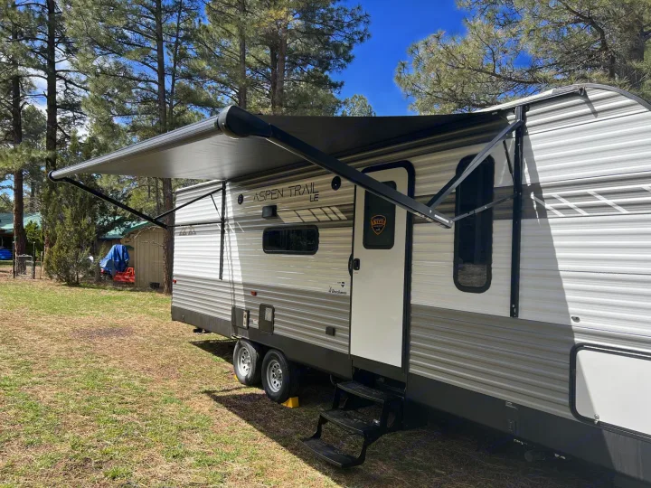 This Aspen Trail RV rental, parked under tall pine trees with its awning extended, is ready for your next outdoor adventure.. Dutchmen Aspen Trail LE 26BH 2022