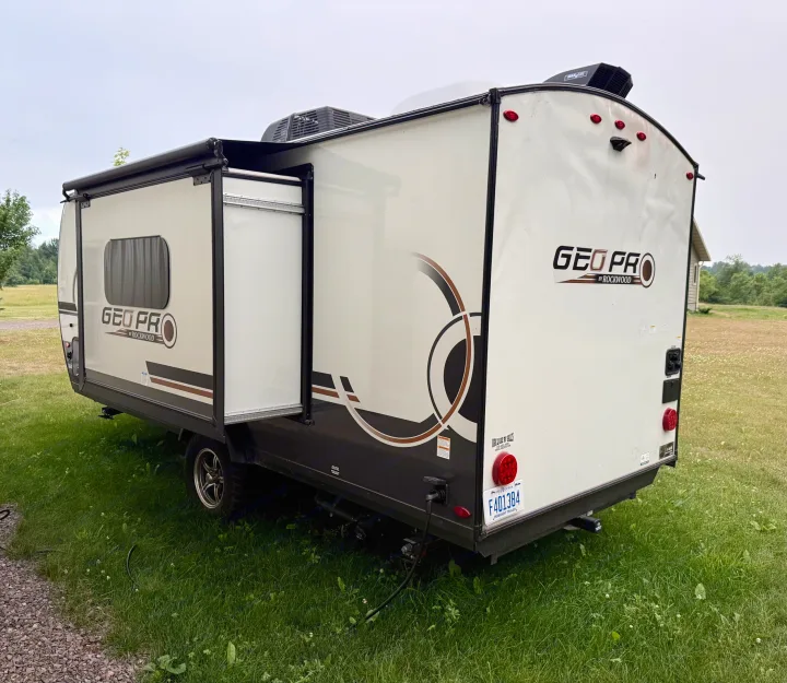 A light-colored GEO PRO by Rockwood travel trailer, perfect for an RV rental, parked on grass with its awning extended.. Forest River Rockwood Geo Pro 2025