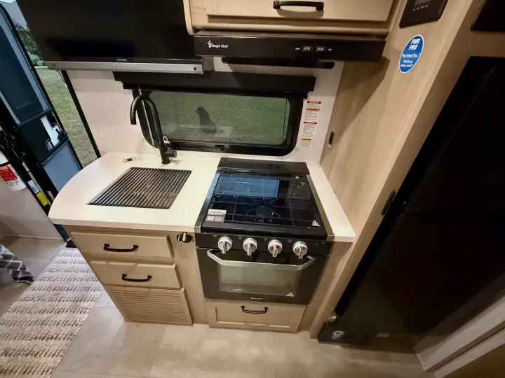 RV rental kitchen: Compact space with a stove, oven, sink, microwave, and refrigerator for convenient travel meals.. Forest River Rockwood Geo Pro 2025
