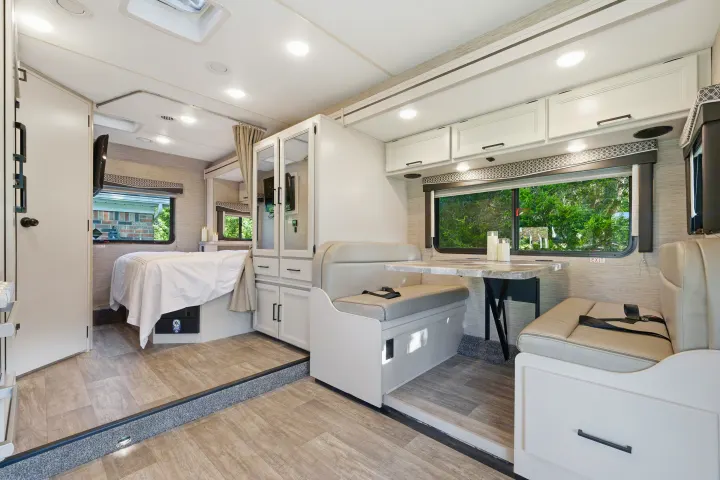 Spacious RV rental interior featuring a bed, dining area, and modern white cabinetry, ideal for comfortable travel.. Thor Chateau 2023