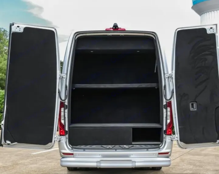 Explore this **RV rental's** organized interior! Open rear doors reveal custom black shelving and storage in a spacious travel van.. Mercedes Benz Executive Lounger by Legends Sprinter 3500xd 170 Ext AWD Executive Lounger 2023