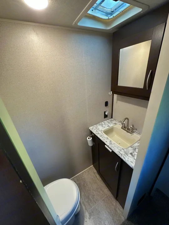 This RV rental features a compact bathroom with a toilet, sink vanity, mirror, and overhead vent.. Sportsmen Sportsmen Fifth Wheel 2018