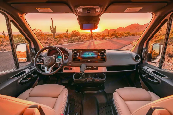 Inside a comfortable Mercedes-Benz RV rental, enjoy a desert sunset with saguaro cacti and a scenic road ahead.. Airstream Interstate 2021