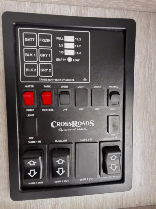 An RV rental control panel showing tank levels, lights, pump, heaters, slide-outs, and awning controls.. Crossroads RV Sunset Trail Super Lite 2024