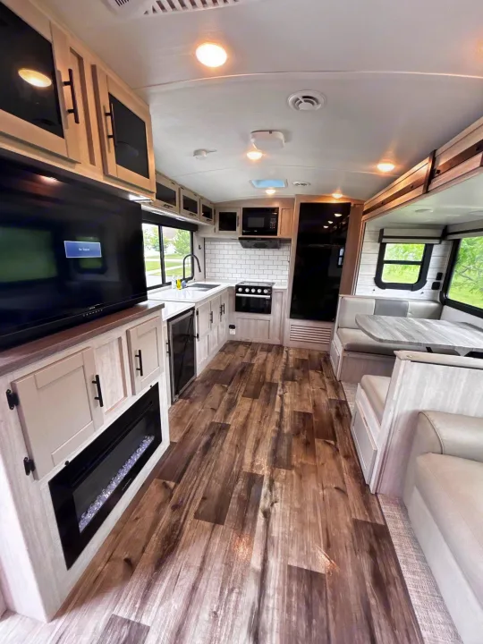 Experience this modern RV rental interior, featuring a full kitchen, dinette, TV, and cozy fireplace, perfect for road trips.. Crossroads RV Sunset Trail Super Lite 2024