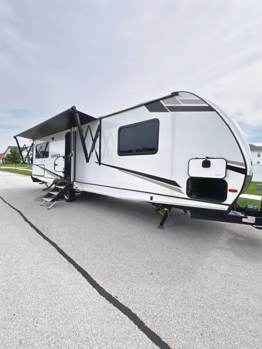 White travel trailer RV rental with awning extended and steps down, ready for your next outdoor adventure.. Crossroads RV Sunset Trail Super Lite 2024