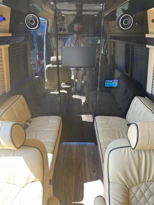 Luxury RV rental interior: cream quilted seats, dark wood-grain walls, floor, mounted TV, and control panel.. Mercedes-Benz 4x4 Sprinter mwb 2020