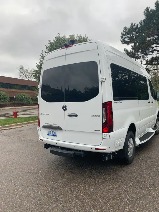 Rear view of a white Mercedes-Benz Sprinter 'Ultimate Toys' luxury rv rental van, 4x4, with tinted windows and a roof antenna.. Mercedes-Benz 4x4 Sprinter mwb 2020
