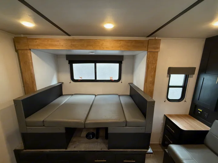 This inviting RV rental features a versatile dinette area with grey upholstered benches, ideal for dining or converting to a bed.. Keystone RV Springdale 2023