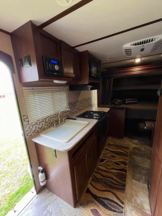 This RV rental offers a compact kitchen with a sink, stove, and microwave, plus cozy bunk beds and AC for comfortable travels.. Jayco Jay Feather Ultra Lite 2015