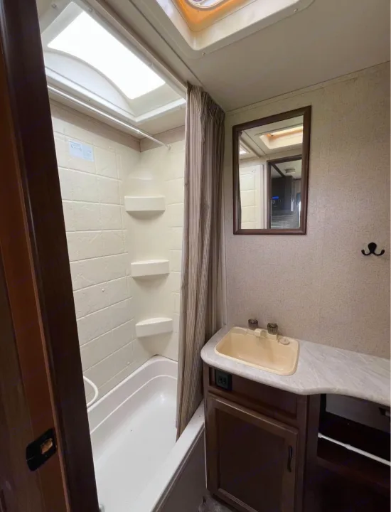Clean RV rental bathroom featuring a tub/shower, sink, mirror, and skylight. Ideal for road trip comfort.. Jayco Jay Feather Ultra Lite 2015
