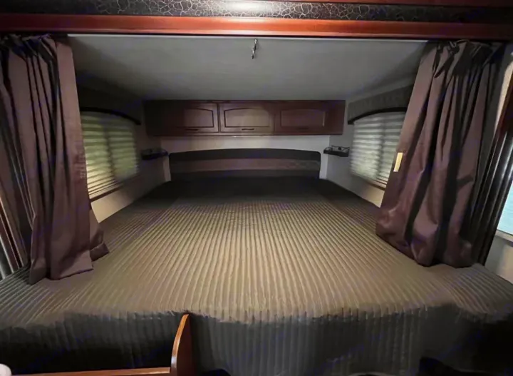 This RV rental bedroom offers a large, comfortable bed, overhead storage, and window privacy curtains and blinds.. Jayco Jay Feather Ultra Lite 2015