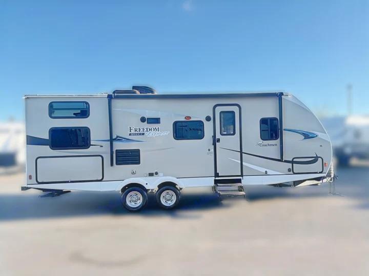 Tan Freedom Express travel trailer, available for RV rental. Parked outdoors on a sunny day, perfect for your next camping adventure.. Coachmen Freedom Express 25SE 2019