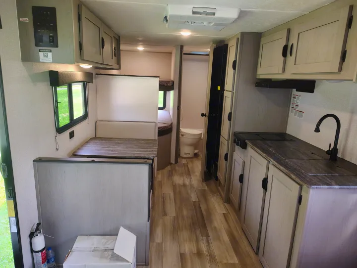 Clean rv rental interior with a bright dinette, efficient kitchen, bunk beds, and compact bathroom—ideal for travel comfort.. Coachmen Clipper 26BH 2024