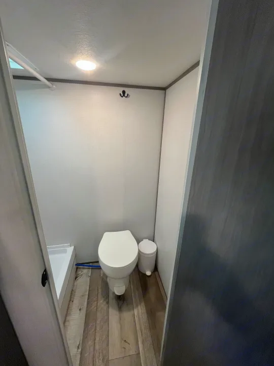 Compact RV rental bathroom features a toilet, shower, and ceiling light. A functional space for travel comfort.. Coachmen 17b 2024