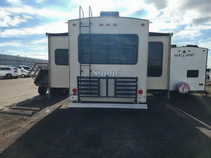RV rental: Sabre fifth wheel, with rear ladder and cargo rack, parked alongside a Mallard RV. A Polaris ATV is behind the Sabre.. Forest River SABRE 2015