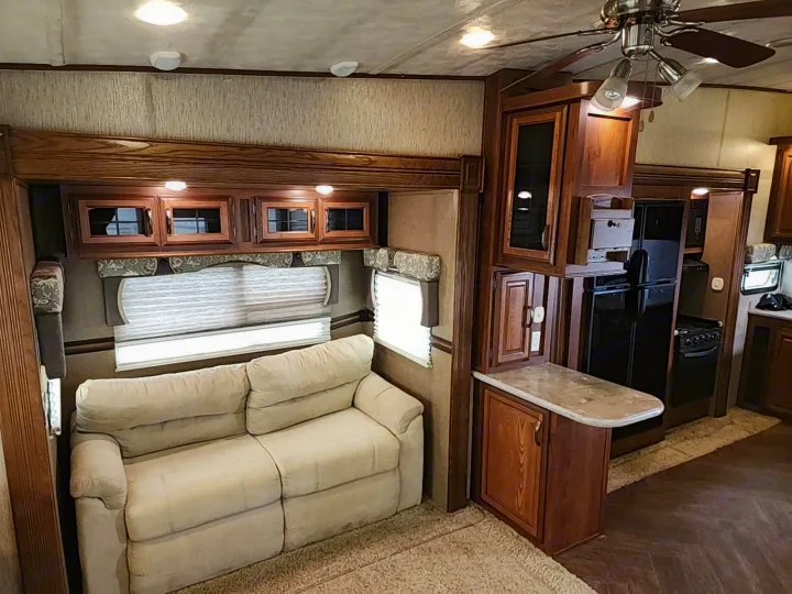 Modern RV rental interior features a cream sofa, kitchen with dark appliances, and elegant wood cabinetry.. Forest River SABRE 2015