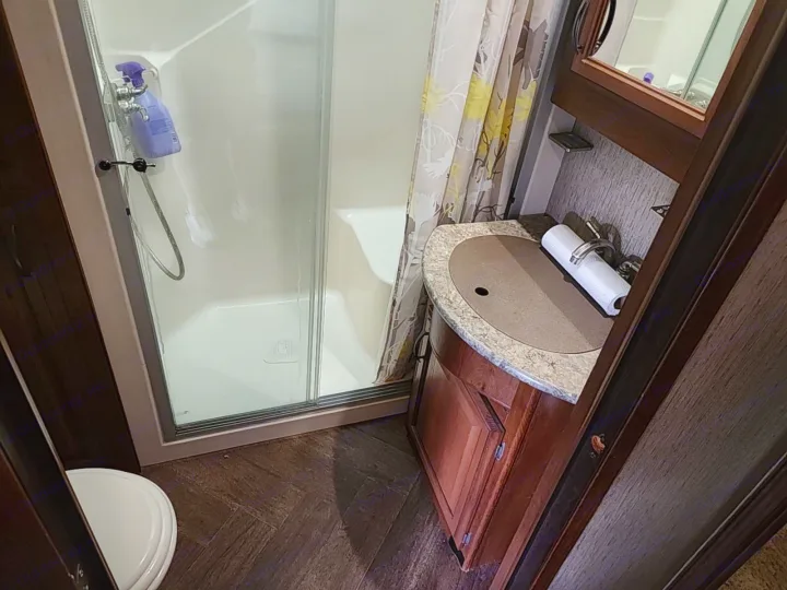 RV rental bathroom: A compact space with a shower stall, vanity sink with a paper towel roll, and a toilet.. Forest River SABRE 2015