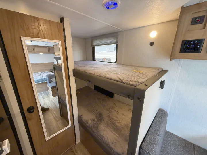 Inside an RV rental showing cozy bunk beds, main sleeping area, and control panel for family travel accommodation.. Forest River Cherokee Wolf Pup 2024