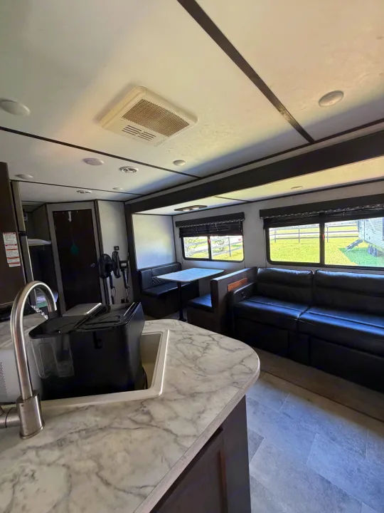 Spacious RV rental interior featuring a modern kitchen, dining booth, and comfy sofa. Perfect for travel.. Dutchmen Coleman Lantern LT 2021