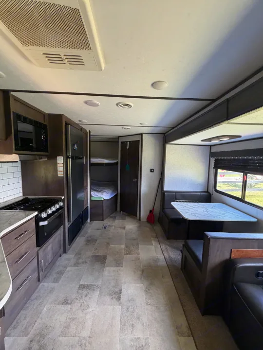 RV rental interior showcasing a well-equipped kitchen, dining area with a window, and bunk beds. Modern design throughout.. Dutchmen Coleman Lantern LT 2021
