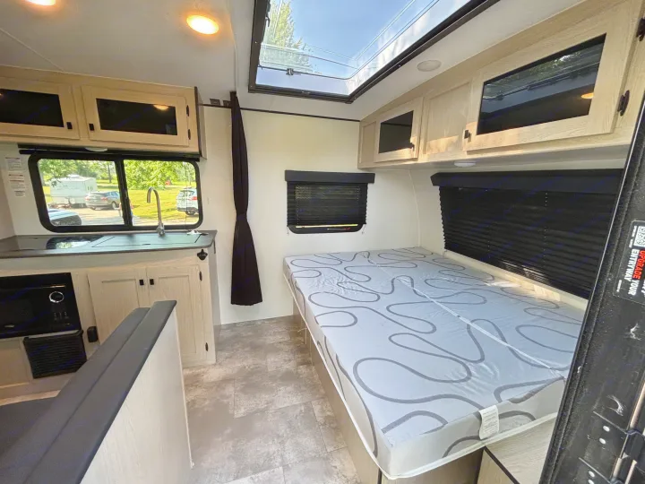 Cozy RV rental interior with kitchen, bed, and skylight. Bright and modern camper setup for your next adventure.. Coachmen Apex Nano 2024