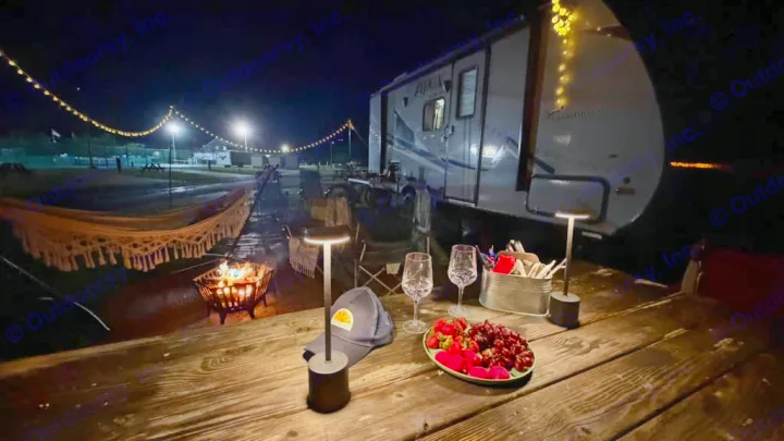 Cozy night at an RV rental: fire pit, hammock, and a romantic snack setup under glowing string lights.. Coachmen Apex 2017