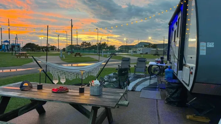 Vibrant sunset at an rv rental campsite. Relax with a picnic table, hammock, and string lights. Enjoy this cozy outdoor setup.. Coachmen Apex 2017