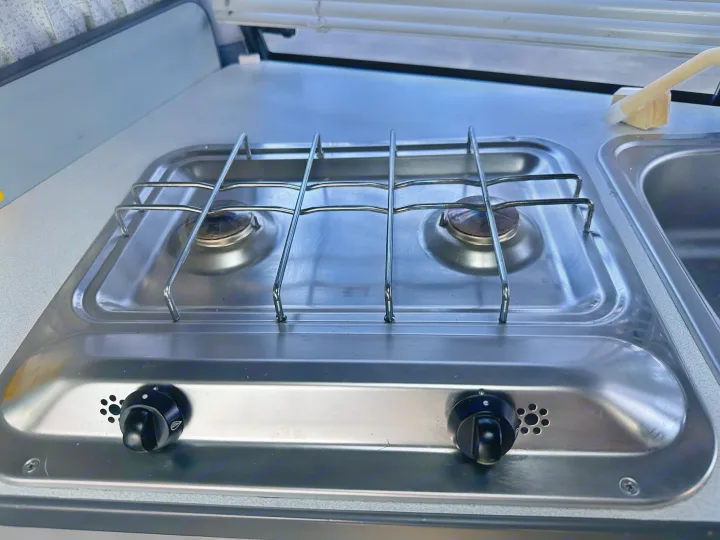 This RV rental features a practical, compact stainless steel two-burner gas stove and sink for travel cooking.. Toyota Hiace Campervan 1994