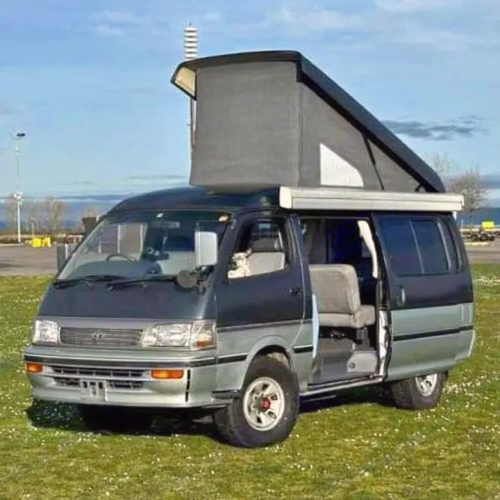 Adventure-ready gray/silver pop-top camper van, doors open, dog peeking. Perfect for an RV rental and exploring the outdoors.. Toyota Hiace Campervan 1994