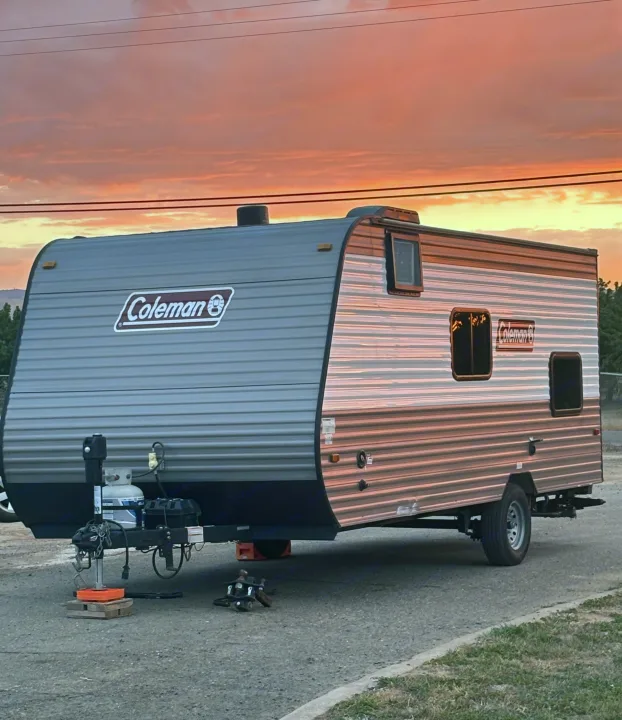 A Coleman RV rental gleams under a vibrant sunset, perfect for camping and road trip adventures.. Dutchmen Coleman Lantern LT 2023