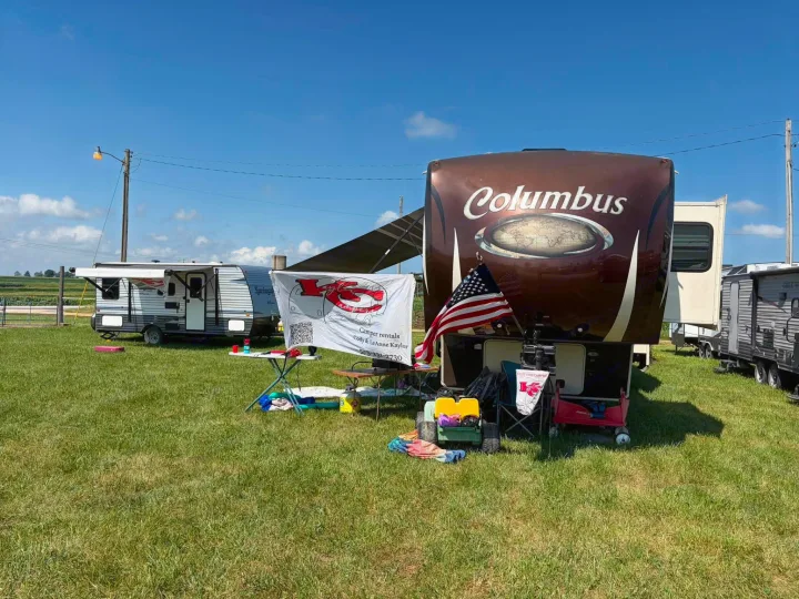 RV rental display featuring a Columbus fifth-wheel & Springdale camper in a sunny field. Banner shows contact info.. Keystone RV Springdale Eco-Lite 2018