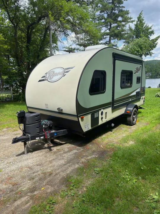 Light green R-Pod travel trailer parked by a lake, ideal for an rv rental adventure among trees.. Forest River R-Pod 2016
