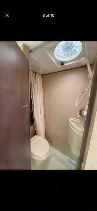 RV rental bathroom with a compact toilet, wall-mounted sink, shower head, and ceiling fan for ventilation.. Forest River R-Pod 2016