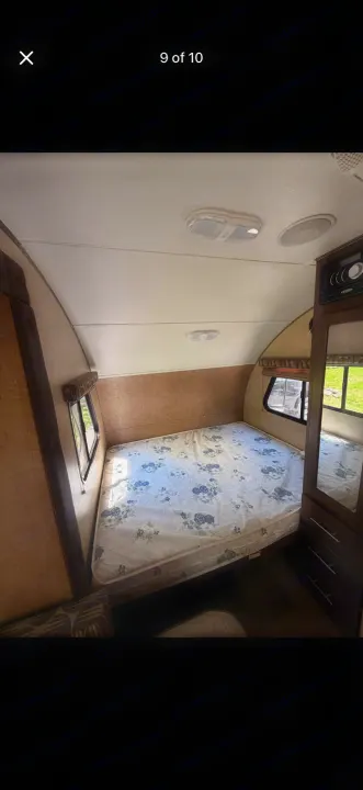 This RV rental's cozy bedroom features a floral mattress, side windows, and a built-in dresser, offering a comfortable retreat.. Forest River R-Pod 2016