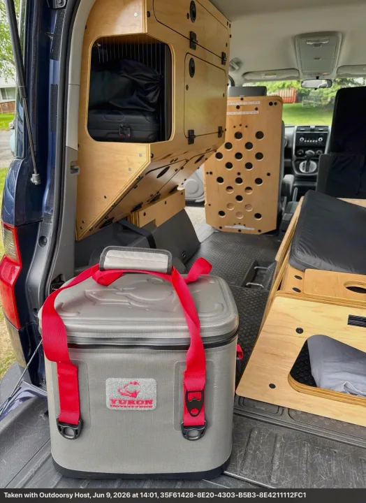 RV rental: Rear view of custom wooden modular interior with shelving, a sleeping area, and a gray soft cooler.. Honda Element 2010