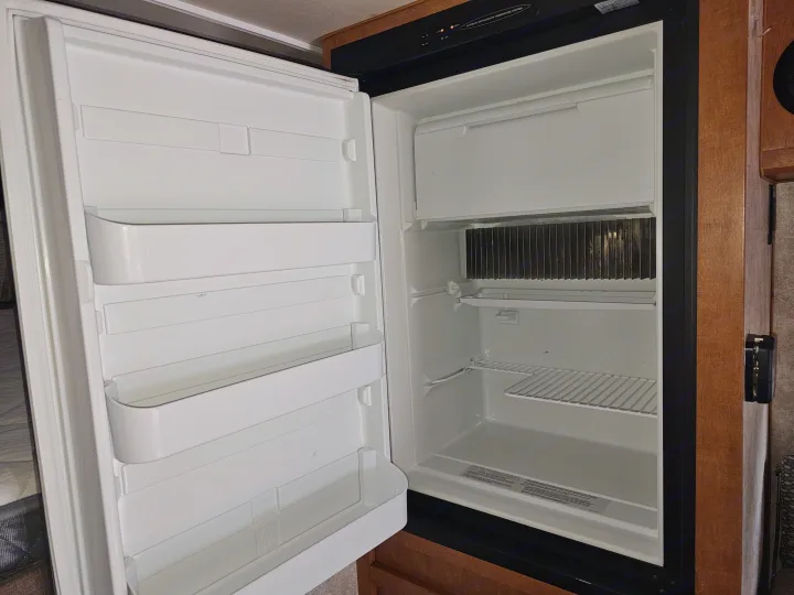 An open, clean RV refrigerator with shelves and a freezer, ready for use during your RV rental. Control panel visible.. Adventurer/F150 ecoboost 80RB 2018