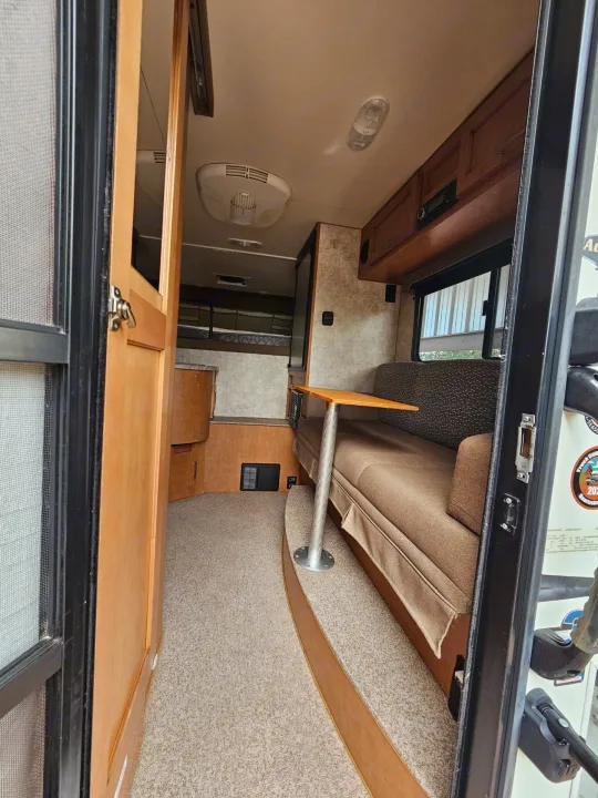 Experience a comfortable RV rental interior: dinette seating, elevated carpet, and a bunk bed in the cozy living space.. Adventurer/F150 ecoboost 80RB 2018