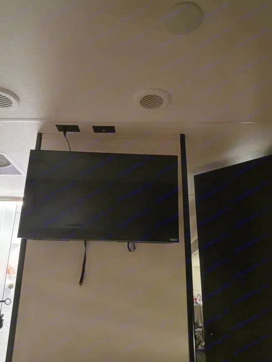 Inside an RV rental: A Vizio TV is mounted on a divider, with ceiling vents and power outlets visible overhead.. Forest River Cherokee Grey Wolf 2026