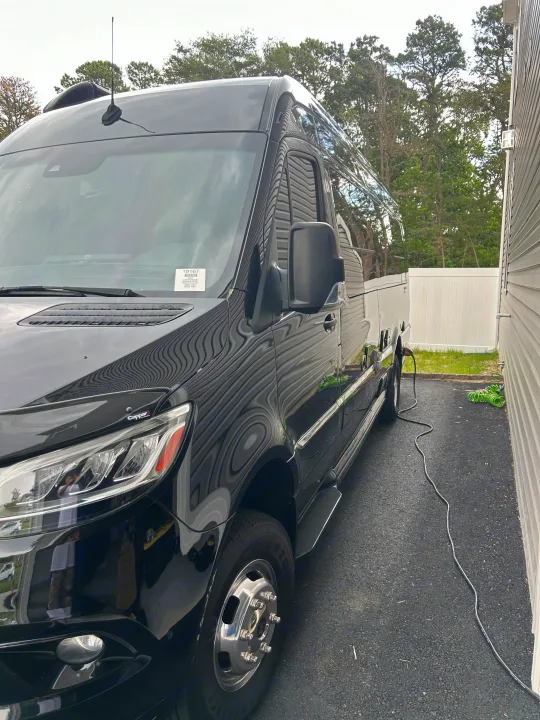 Black Airstream Interstate RV rental, based on a Sprinter van, parked and charging its battery.. Airstream Interstate 2021