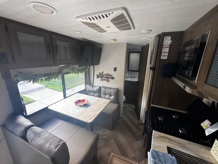 Spacious and modern RV rental interior with kitchen, dining area, and bathroom access. Adventure awaits!. Forest River Wildwood X-Lite 2021