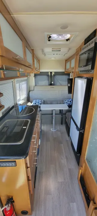 This rv rental features a modern interior: compact kitchen, dining area with bench seating, overhead storage, microwave, and refrigerator.. Coachmen Crossfit 2019
