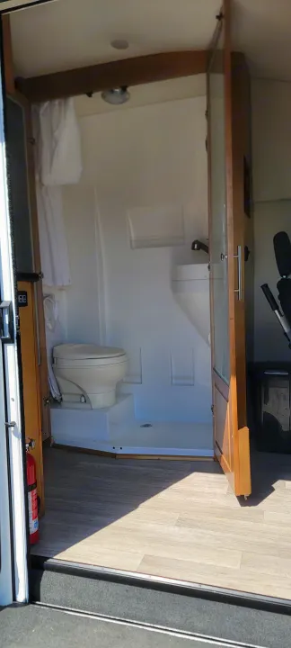 RV rental compact wet bath: toilet, shower, and small faucet inside, with a fire extinguisher nearby.. Coachmen Crossfit 2019