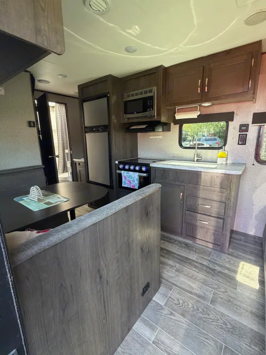 Spacious RV rental interior featuring a full kitchen with microwave, stove, sink, and refrigerator, plus a comfy dinette.. Jayco Jay Flight SLX 2021