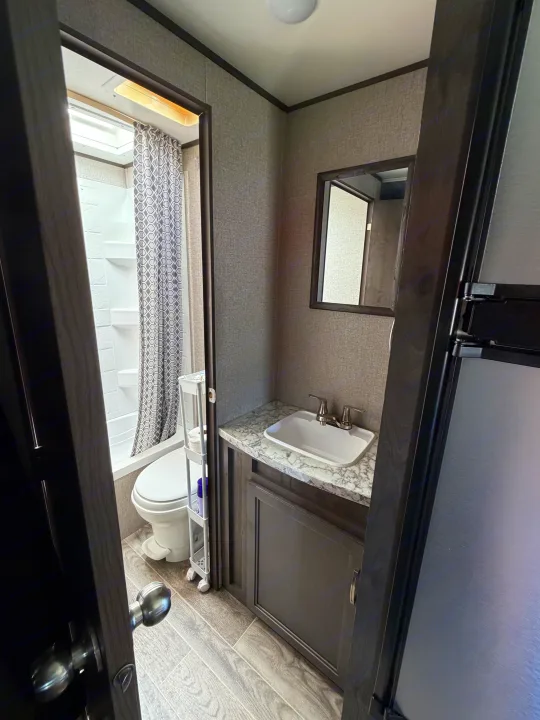 RV rental bathroom view: shower, toilet, and vanity with sink & mirror visible. Compact yet functional space inside an RV.. Jayco Jay Flight SLX 2021